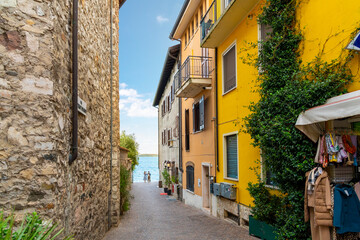 Fototapeta na wymiar A narrow alley of shops and cafes leading to the lakefront promenade at the town of Sirmione, Italy, on the shores of Lake Garda.
