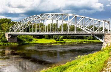Steel arch bridge across the Msta river in summer sunny day