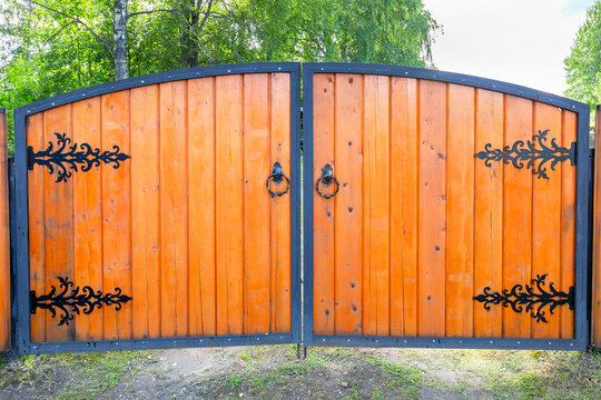 Big wooden gate with metal knobs and door hinges