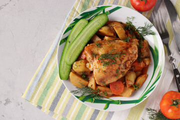 Chicken thighs cooked with potatoes and carrots on gray table, Top view