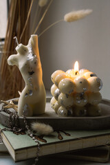 A bubble candle and a white candle shaped as a female body on a concrete tray