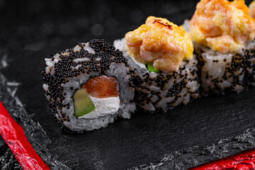 Asian cuisine. Rolls Nagano. Rice nori caviar tobiko cremette cheese avocado parmesan on a black background.