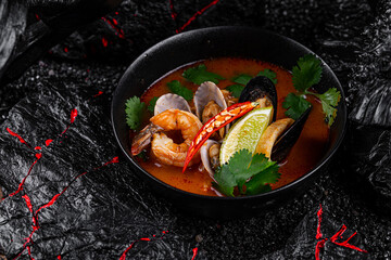 Tom Yum in einem Teller auf schwarzem Hintergrund