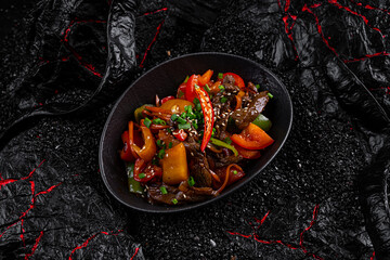 Wok pepper beef in a plate on a black background
