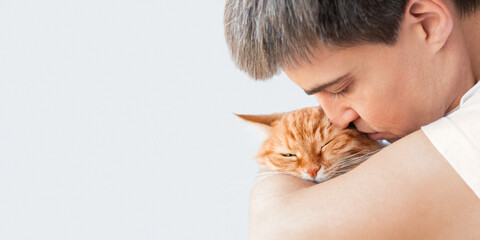 Close up portrait of Caucasian man cuddling cute ginger cat. Tender relationship with fluffy pet...