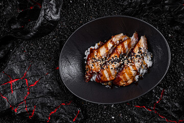 Asian cuisine. warm salad with eel in a plate on a black background. Tiger prawns croutons cherry parmesan