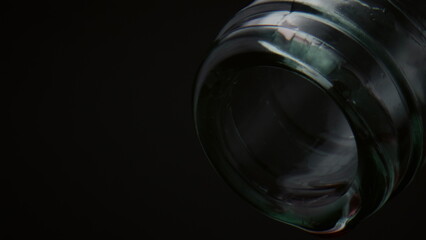Closeup waterdrop drip bottle neck on black background. Droplets falling down.