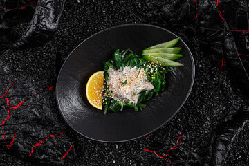Asian cuisine. Chuka salad in a black plate on a black background.