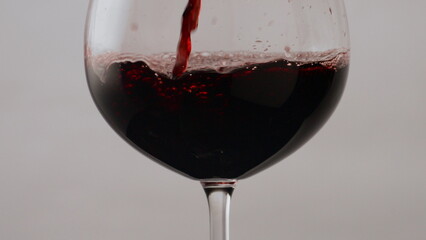 Burgundy wine pouring glass goblet in super slow motion closeup. Drink flowing 