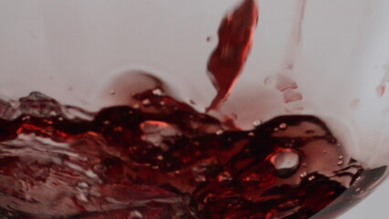 Closeup red wine stream filling empty crystal goblet in super slow motion.