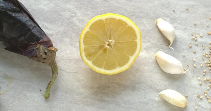 Ingredients for Mutabbal - middle eastern smoky eggplant and  sesame dip: fire roasted eggplant, lemon, garlic, sesame seeds and Muttabbal in bowl sprinked with berbere spice blend. Camera slide