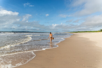 An adult woman in a bikini walking under strong sunlight on beach