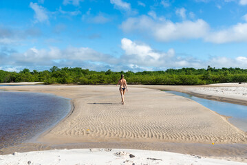 An adult woman in a bikini walking under strong sunlight on beach