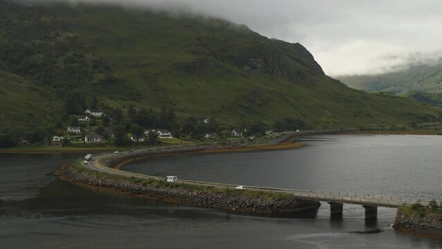 Aerial flyover view of cars driving on bridge over lake / Ault a'chruinn, Scotland