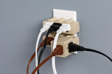 Electrical outlet overloaded with extension cords and adapters. Electricity safety, fire hazard and circuit overload concept - obrazy, fototapety, plakaty