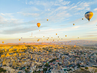 Breathtaking drone view of hundreds of hot air balloons ride over Turkey's iconic Cappadocia, the city in the middle of fairy chimneys valley during the sunrise. High quality photo