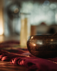Tibetan singing bowl on a red carpet with white candle in the background during sacred spiritual ceremony in Tulum