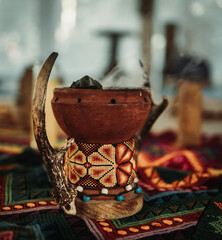 Incense burner with horn on a colorful blanket with indigenous pattern and blurry background during spiritual ceremony in Tulum