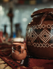 Ceramic cup with big jar painted with indigenous pattern and blurry background during cacao ceremony in Tulum