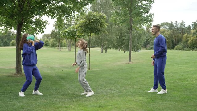 A family is playing volleyball on a walk in the park. Father and daughter actively spend time playing sports in nature. The concept of a happy family together, people's smiles, fun. High quality 4k 