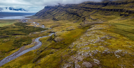 birdview of tundra field, rivers, sky and clouds over mountain ridge