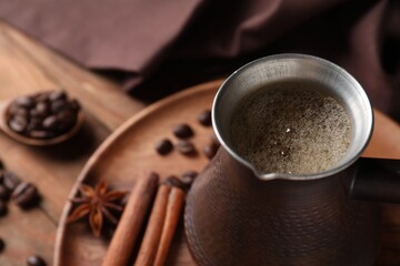 Cezve with Turkish coffee, beans and spices on wooden table, closeup. Space for text