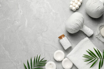 Flat lay composition with herbal massage bags and other spa products on grey marble table, space...