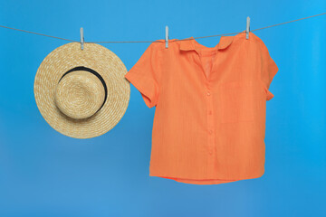 Hat and shirt drying on laundry line against light blue background