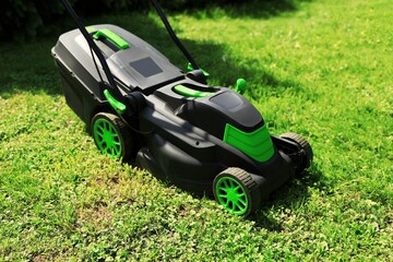 Cutting green grass with lawn mower in garden