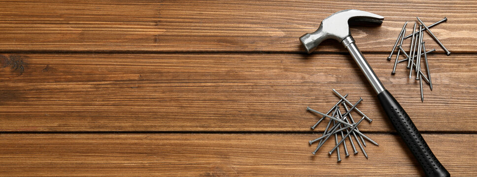 Hammer And Metal Nails On Wooden Table, Flat Lay With Space For Text. Banner Design