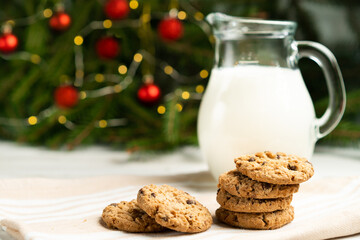 milk and cookies on the table against the backdrop of the Christmas tree, a treat for Santa Claus, Christmas traditions