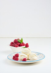 Vanilla ice cream balls with red raspberries in a round plate