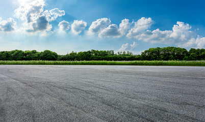 Empty asphalt road and green forest with sky clouds background