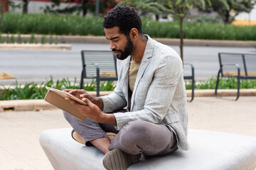 Afro-American man working in a tablet in the street 