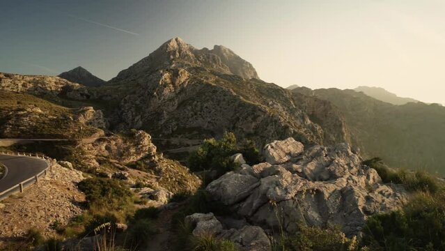 Panning shot of illuminated serpentine roads at Nus de Sa Corbata, Mallorca during sun rays at sunset