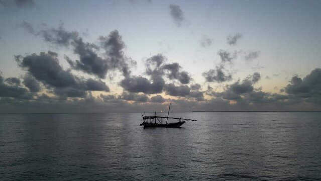Silhouette of fishing boat Uroa beach Zanzibar Island floating near the shore during sunset, Aerial hovering, shot