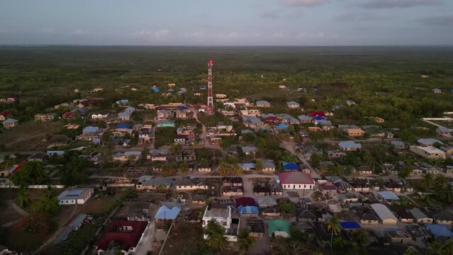 Radio tower and homes at Uroa Beach town in Zanzibar Tanzania Africa, Aerial approach shot