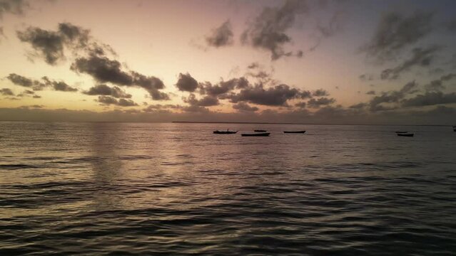 Small fishing boats in shallow waters at Uroa beach Zanzibar Island during sunset, Tanzania Africa, Aerial flyover shot