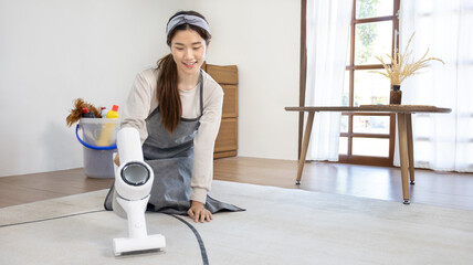 Fototapeta na wymiar Beautiful woman vacuuming the floor and pillow of her living room, Big cleaning in the house, Removes germs and dirt and deep stains, Housewife cleaning, Keeping her home clean, Domestic hygiene.