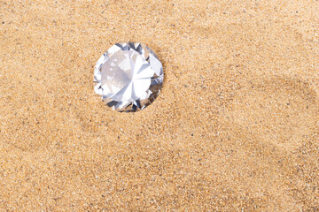 Fototapeta na wymiar Big Carat Diamond Jewelry Gemstone on Sand Beach in Tropical Island beautiful summer sun on golden find sand, studio shot copy space