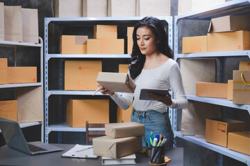 Asian Start-up businesswoman cheking serial number of boxes with checklist Freelancers picking up a...