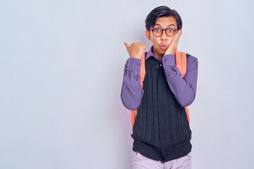 Wow, attention to advertising! excited young Asian student man with a backpack pointing Finger at...