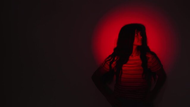 Image Of A Woman On The Wall With A Red Light Spotlight. Medium Shot 