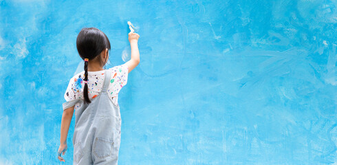 Banner of unidentified little girl is  painting the wall with water color at home, concept of art education for kid, homeschooling and learning activity by playing for child.