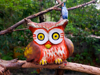 A carved painted wooden owl stands on a branch