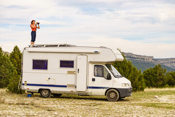 Woman traveling with caravan, taking photo from rv roof - obrazy, fototapety, plakaty