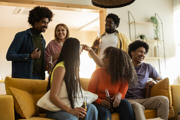 Multiracial group of friends gathered around the sofa with some beers. Friendship concept
