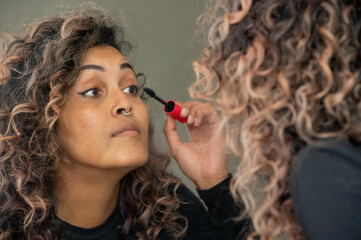 Obraz premium Portrait of woman applying eyeliner in mirror