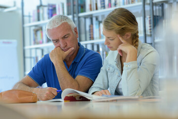 Fototapeta premium two people in library looking through book