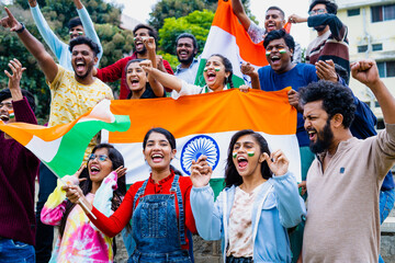 Group of audience at stadium shouting, screaming for win by holding indian flags while watching...